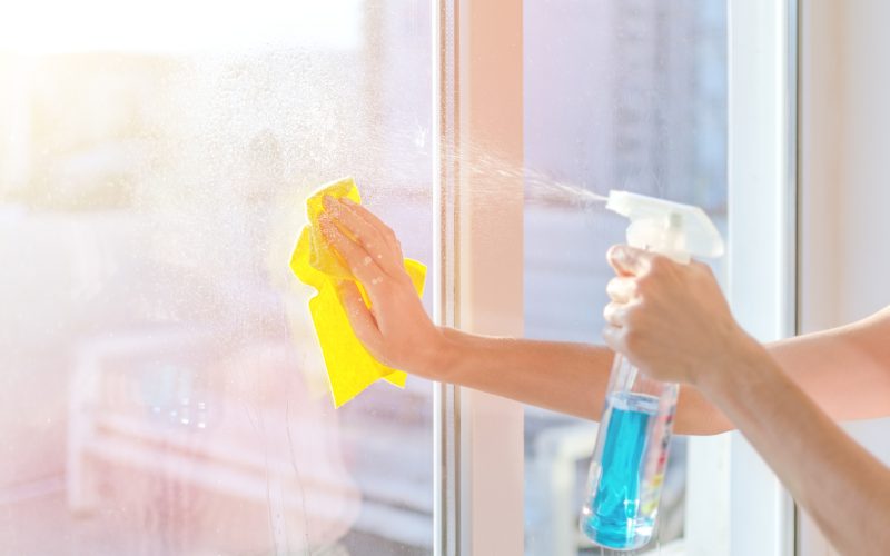 Hands with napkin cleaning window. Washing the glass on the windows with cleaning spray. Selective soft focus. Empty place for text, copy space. Window cleaning home.